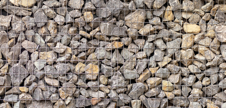 Rugged gabion wall of stones with grid pattern for construction and landscape use