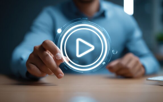 Hand touches glowing digital play button interface above wooden desk.