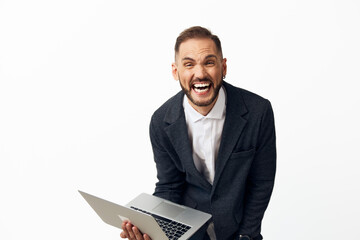 Professional business man with a laptop stands against a clean colored background, projecting energy, confidence, and excitement through his expressive smile.