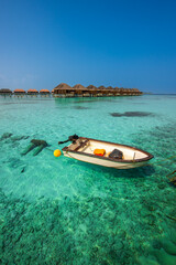 Fototapeta premium Tranquil closeup calm sea water waves with palm trees. Boat and bungalows background. Tropical island beach landscape exotic shore coast. Summer vacation, holiday amazing nature, Maldives.