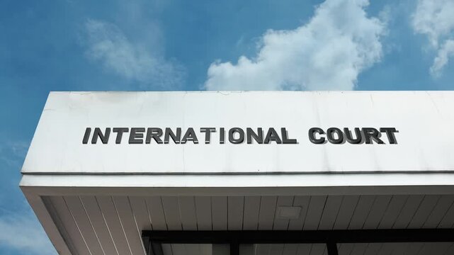 International Court word sign prominently displayed on the official judicial building facade beneath a clear blue sky, signifying a global tribunal dedicated to resolving disputes or prosecuting crime