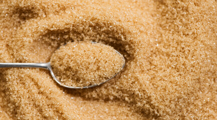 Brown Cane sugar in a spoon close up. Heathy eating, diet concept. Grained brown sugar background,...