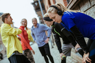 Young group of people stretching before running and jogging together in the city during colder weather in the winter and autumn months