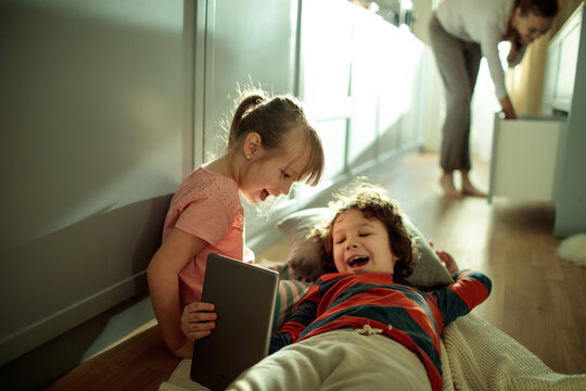 Young children playing with tablet at home - Powered by Adobe