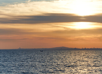 Serene sunset over calm ocean waters, with gentle waves reflecting warm hues of orange and gold, creating a tranquil atmosphere, ideal for relaxation and peaceful moments by the sea