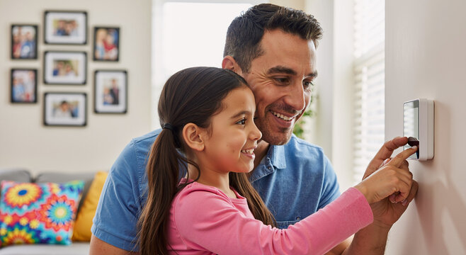father and daughter adjusting home thermostat in living room smiling and bonding together - Powered by Adobe