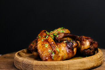 Delicious grilled chicken wings garnished with herbs on wooden plate