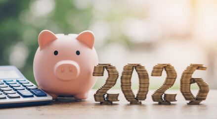 piggy bank and stacked coins form 2026 with calculator on wooden table, saving for future