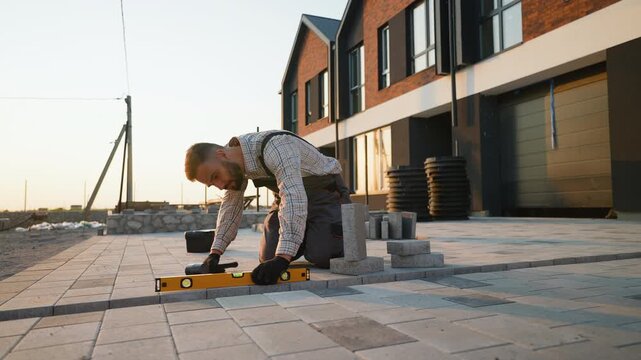 Construction worker laying concrete paving slabs