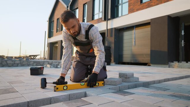 Professional paver installing concrete paving blocks outdoors