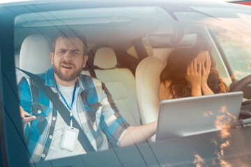 Frightened woman crying and covering her face with her hands while sitting in the driver seat, male instructor confused. Driving test, driver courses, exam concept