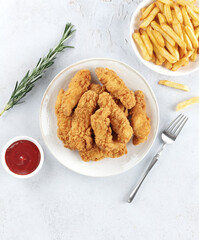 Crispy chicken strips with ketchup and French fries on a white background. Fast food. 
