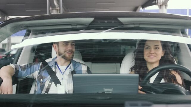 Instructor checking while woman passing exam at driving school. Slow motion
