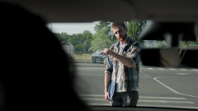 Male driving instructor showing how to parking for lady outdoors. Slow motion