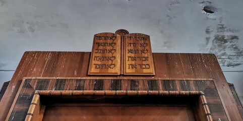 The 10 commandments list plaque in derelict synagogue. Jewish biblical monument decoration, hebrew ten laws Torah tablets. Carved statue sign in crumbling abandoned church. Forgotten faded faith 