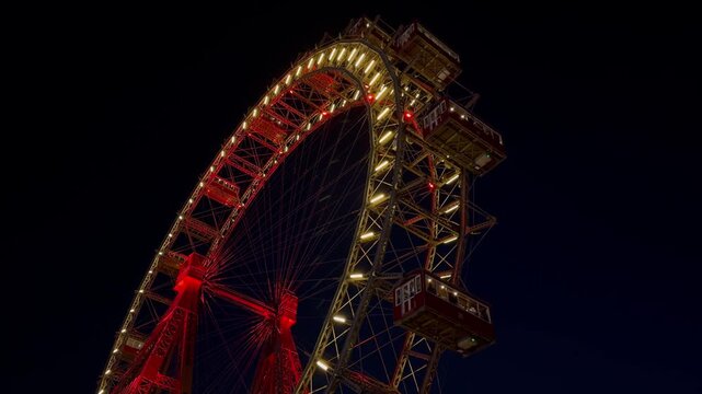 The Wiener Riesenrad, Illuminated giant Ferris Wheel glowing at night against dark sky at Prater Amusement Park, Vienna