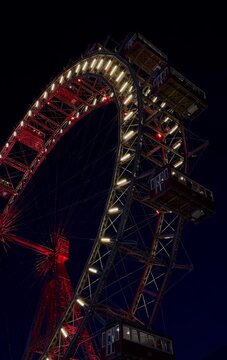 The Wiener Riesenrad, Illuminated giant Ferris Wheel glowing at night against dark sky at Prater Amusement Park, Vienna