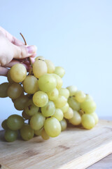 A bunch of fresh green grapes resting on a rustic wooden board