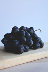 A close-up of a bunch of blue grapes lying on a rustic wooden board - Soft focus