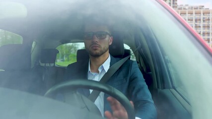 Confident attractive elegant man in business suit driving car in the city. Transport, business and people concept. Slow motion