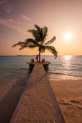 Tranquil closeup calm sea water waves with palm trees. Tourist posing at sunset time. Tropical island beach landscape exotic shore coast. Summer vacation, holiday amazing nature, Maldives.