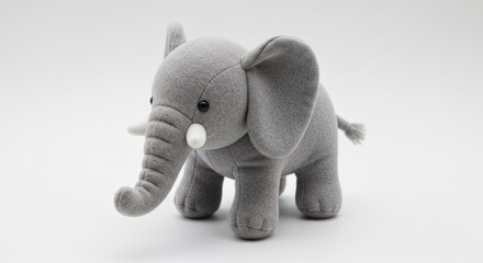 Plush gray elephant toy with button eyes and white tusks on white backdrop