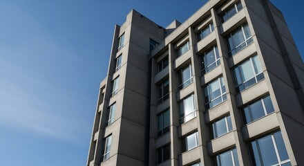 Explore the geometric simplicity of this concrete office building against a clear blue sky, perfect for showcasing urban architecture and modern cityscapes in your next project