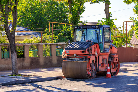 Vibrant industrial red steamroller on sunny residential neighborhood street