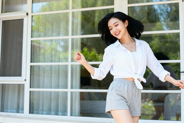 A young woman in casual clothing standing outdoors with a bright smile