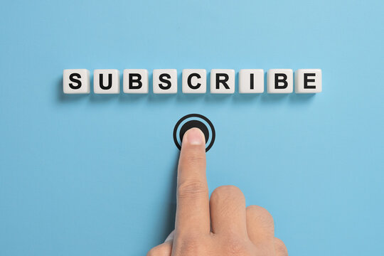 Male hand pressing subscription button with the word subscribe written on dice. Concept of online registration.