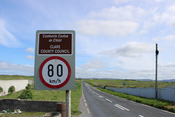 County Council speed limit sign on the N67 Road in County Clare, Ireland in Irish Gaelic and English on a sunny day