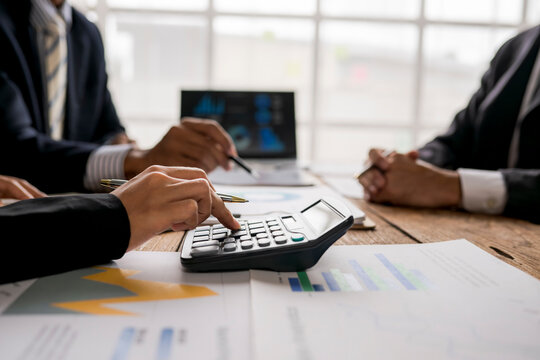 Business team reviewing financial reports and using calculator during a meeting - Powered by Adobe