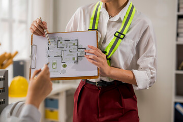 Architect showing blueprint to colleague during meeting in office
