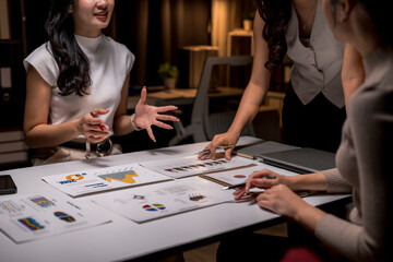 Fototapeta premium Asian businesswomen discussing business performance analyzing charts in office at night