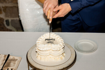 A beautiful moment captured as the couple cuts their wedding cake together — hands intertwined over a delicate “Just Married” design, symbolizing unity, joy, and new beginnings