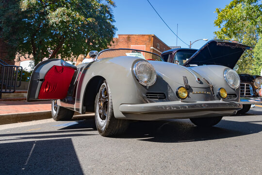 Vintage Porsche 356 roadster on display with its door open at a classic car show.