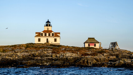 Egg Rock lighthouse is seen from water under sunset