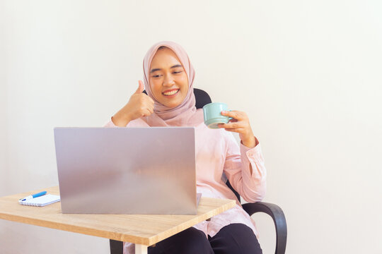Young jilbab woman professional enjoying coffee while working