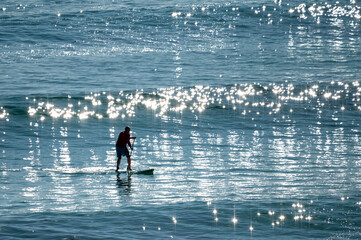 Active senior Australian man ride on a wave with SUP in the Pacific ocean