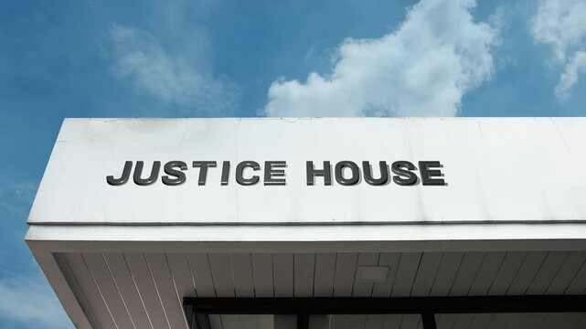 Justice House word sign displayed on building facade under clear blue sky, representing legal authority, judicial administration, and the headquarters of the government's legal branch.