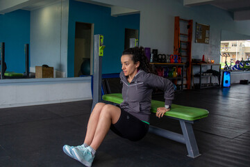 Woman doing triceps dips on gym bench