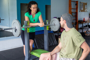 Personal trainer coaching man during gym bench press workout