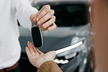 Salesperson handing over car keys to customer, showcasing successful car purchase transaction in dealership environment, highlighting customer satisfaction and excitement