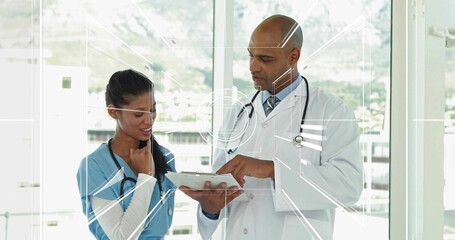 white-coat doctor and blue-scrubs nurse reviewing tablet in hospital hallway with stethoscopes