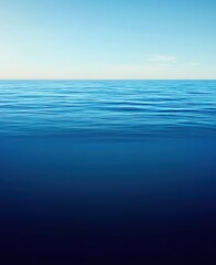 Fototapeta premium Calm ocean water surface extending to a clear horizon under a bright blue sky, creating a serene minimalist backdrop