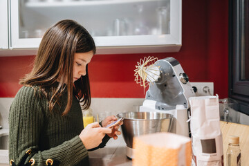Girl using phone checking recipe for baking cake