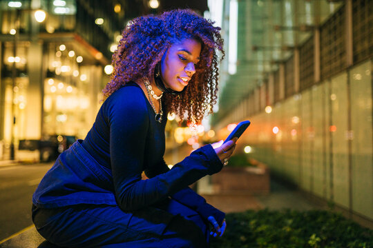 Young woman using smartphone at night in the city