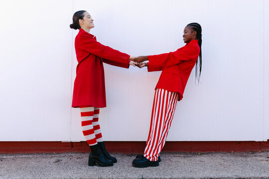 Two fashion models holding hands wearing red clothes