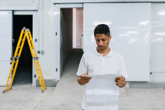 Thoughtful man with papers standing in warehouse