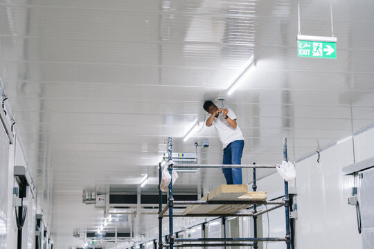 Focused man installing security camera on ceiling